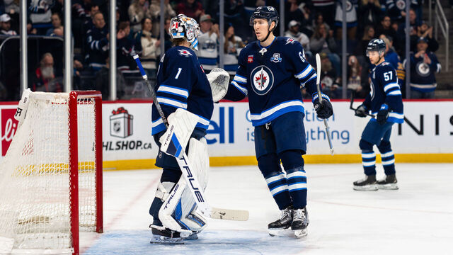WINNIPEG, CANADA - DECEMBER 5: Eric Comrie #1 and Logan Stanley #64 of the Winnipeg Jets celebrate a 4-1 victory against the Buffalo Sabres at Canada Life Centre on December 5, 2025 in Winnipeg, Manitoba, Canada.