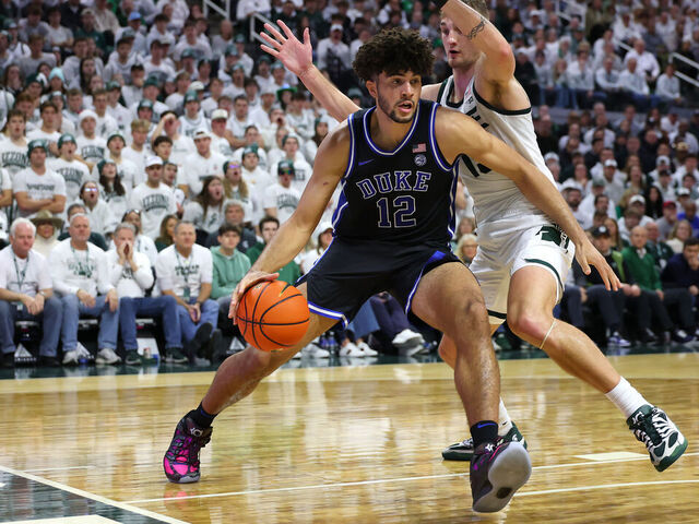 EAST LANSING, MICHIGAN - DECEMBER 06: Cameron Boozer #12 of the Duke Blue Devils drives around Carson Cooper #15 of the Michigan State Spartans during the second half at Breslin Center on December 06, 2025 in East Lansing, Michigan.