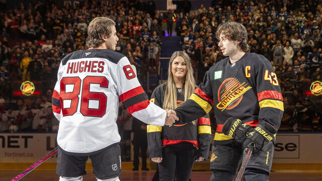 VANCOUVER, CANADA - OCTOBER 30: Quinn Hughes #43 of the Vancouver Canucks and Jack Hughes #86 of the New Jersey Devils face off for the ceremonial puck drop with firefighter, Liz Rose before their NHL game at Rogers Arena on October 30, 2024 in Vancouver, British Columbia, Canada.