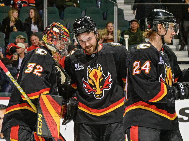CALGARY, ALBERTA - DECEMBER 06: Dustin Wolf #32 and Rasmus Andersson #4 of the Calgary Flames celebrate a win against the Utah Mammoth at the Scotiabank Saddledome on December 06, 2025 in Calgary, Alberta.