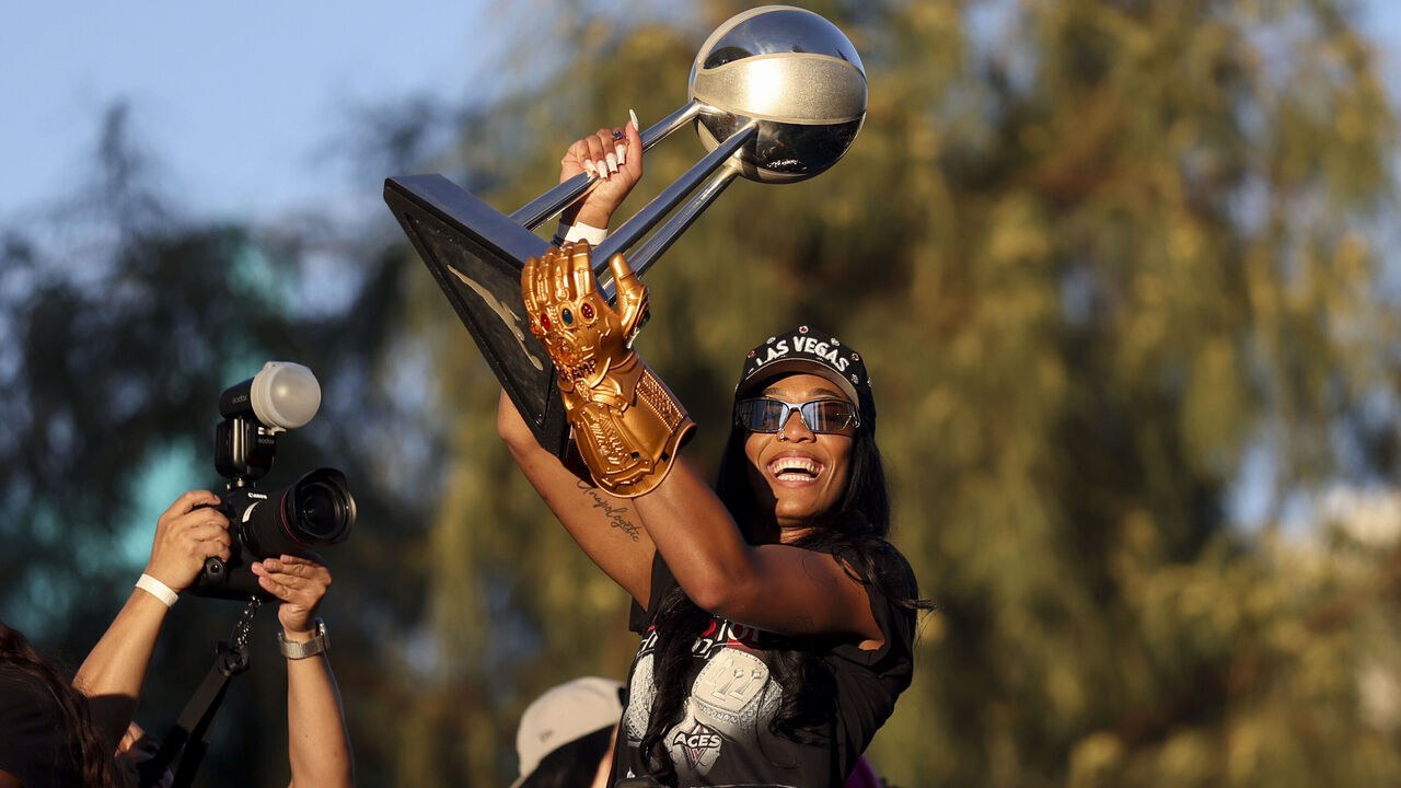LAS VEGAS, NEVADA - OCTOBER 17: A'ja Wilson #22 of the Las Vegas Aces lifts the 2025 WNBA championship trophy as she rides on top of a bus during the team's WNBA championship victory parade and rally at Toshiba Plaza on October 17, 2025 in Las Vegas, Nevada. The Aces defeated Phoenix Mercury on October 10 in Game Four of the 2025 WNBA Playoffs finals to win the 2025 title. NOTE TO USER: User expressly acknowledges and agrees that, by downloading and or using this photograph, User is consenting to terms and conditions of the Getty Images License Agreement.