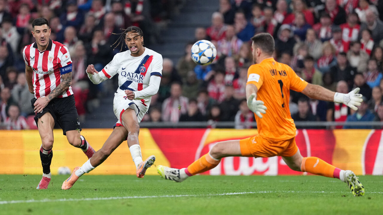 TOPSHOT - Paris Saint-Germain's French forward #29 Bradley Barcola challenges Athletic Bilbao's Spanish goalkeeper #01 Unai Simon during the UEFA Champions League league phase day 6 football match between Athletic Club Bilbao and Paris Saint-Germain (PSG) at San Mames Stadium in Bilbao on December 10, 2025.