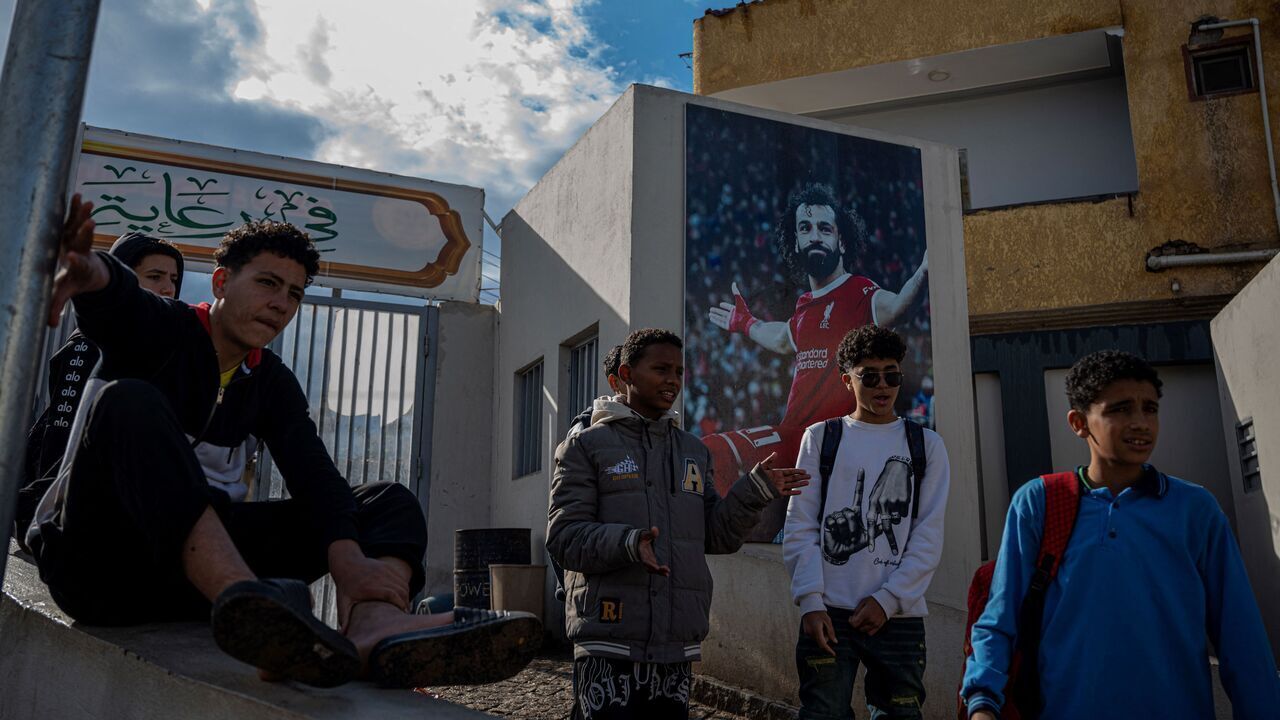 Footballers stand next a picture of Liverpool's footballer Mohamed Salah at his Youth Centre in the Egyptian village of Nagrig, about 120 kilometres northwest of Cairo on December 10, 2025. Salah, the Egypt international was omitted from the squad that travelled to Milan for a Champions League clash with Inter on December 9 following a blistering attack on manager Arne Slot and the club hierarchy after being left on the bench for last weekend's 3-3 draw at Leeds.
