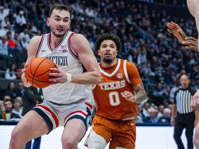 HARTFORD, CONNECTICUT - DECEMBER 12: Alex Karaban #11 of the Connecticut Huskies goes past Jordan Pope #0 of the Texas Longhorns during the second half of the NCAA men's basketball game at PeoplesBank Arena on December 12, 2025 in Hartford, Connecticut.
