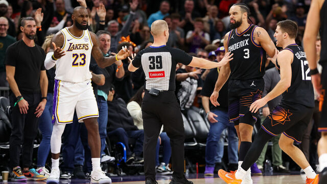 PHOENIX, ARIZONA - DECEMBER 14: An official comes between Lebron James #23 of the Los Angeles Lakers and Dillon Brooks #3 of the Phoenix Suns during the second half of a game at Mortgage Matchup Center on December 14, 2025 in Phoenix, Arizona.