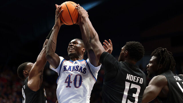 LAWRENCE, KANSAS - DECEMBER 16: Flory Bidunga #40 of the Kansas Jayhawks grabs a rebound over Jack Doumbia Jr. #21 and Chike Ndefo #13 of the Towson Tigers during the game at Allen Fieldhouse on December 16, 2025 in Lawrence, Kansas.