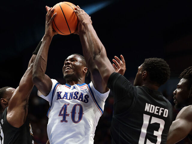 LAWRENCE, KANSAS - DECEMBER 16: Flory Bidunga #40 of the Kansas Jayhawks grabs a rebound over Jack Doumbia Jr. #21 and Chike Ndefo #13 of the Towson Tigers during the game at Allen Fieldhouse on December 16, 2025 in Lawrence, Kansas.