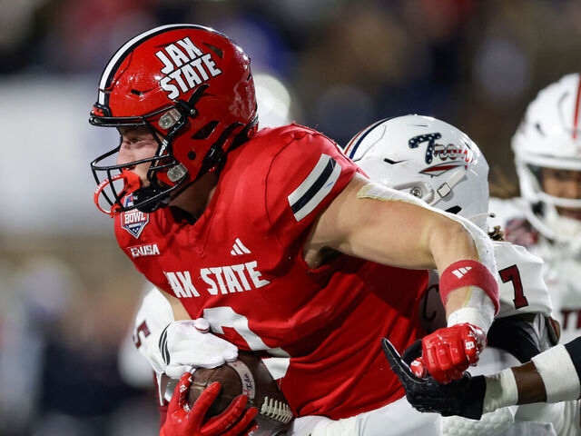 MONTGOMERY, ALABAMA - DECEMBER 16: Brock Rechsteiner #3 of the Jacksonville State Gamecocks is tackled by Jordan Stringer #7 of the Troy Trojans in the first half during the IS4S Salute To Veterans Bowl at Cramton Bowl on December 16, 2025 in Montgomery, Alabama.