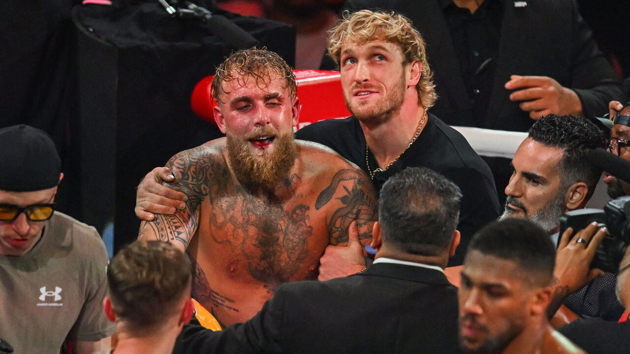 YouTuber Logan Paul (R) holds his brother, US boxer and influencer Jake Paul, after he lost to British boxer Anthony Joshua (off frame) in a nontitle heavyweight bout at the Kaseya Center in Miami, Florida, on December 19, 2025.
