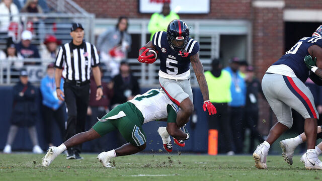 OXFORD, MISSISSIPPI - DECEMBER 20: Kewan Lacy #5 of the Ole Miss Rebels is tackled by Kevin Adams III #7 of the Tulane Green Wave during the first half of the 2025 College Football Playoff First Round Game at Vaught-Hemingway Stadium on December 20, 2025 in Oxford, Mississippi.