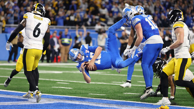 DETROIT, MICHIGAN - DECEMBER 21: Jared Goff #16 of the Detroit Lions leaps into the end zone to score a fourth quarter touchdown against the Pittsburgh Steelers at Ford Field on December 21, 2025 in Detroit, Michigan. The touchdown was nullified due to offensive pass interference by Amon-Ra St. Brown #14 of the Detroit Lions.