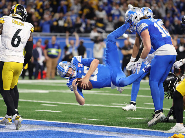 DETROIT, MICHIGAN - DECEMBER 21: Jared Goff #16 of the Detroit Lions leaps into the end zone to score a fourth quarter touchdown against the Pittsburgh Steelers at Ford Field on December 21, 2025 in Detroit, Michigan. The touchdown was nullified due to offensive pass interference by Amon-Ra St. Brown #14 of the Detroit Lions.