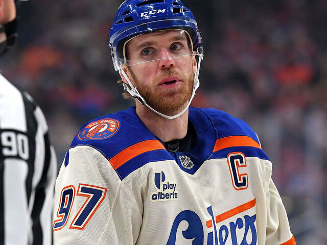 EDMONTON, CANADA - DECEMBER 23: Connor McDavid #97 of the Edmonton Oilers has a conversation with linesperson Travis Toomey #90 during a stoppage in play in the first period of the game against the Calgary Flames at Rogers Place on December 23, 2025, in Edmonton, Alberta, Canada.