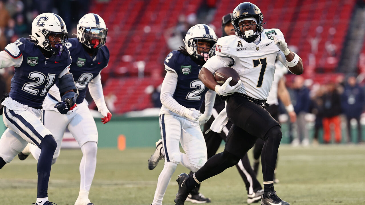 BOSTON, MA - DECEMBER 27: Godspower Nwawuihe #7 of the Army Black Knights looks back as he runs past Lee Molette III #21 of the UConn Huskies and Devin Pringle #2 for a touchdown during the first half of the Wasabi Fenway Bowl at Fenway Park on December 27, 2025 in Boston, Massachusetts.