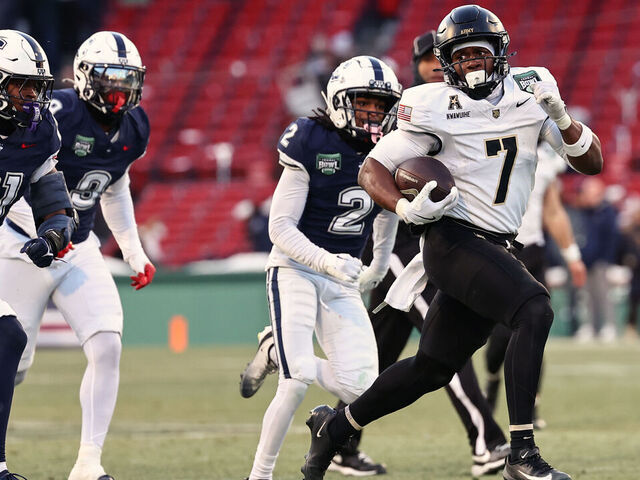 BOSTON, MA - DECEMBER 27: Godspower Nwawuihe #7 of the Army Black Knights looks back as he runs past Lee Molette III #21 of the UConn Huskies and Devin Pringle #2 for a touchdown during the first half of the Wasabi Fenway Bowl at Fenway Park on December 27, 2025 in Boston, Massachusetts.