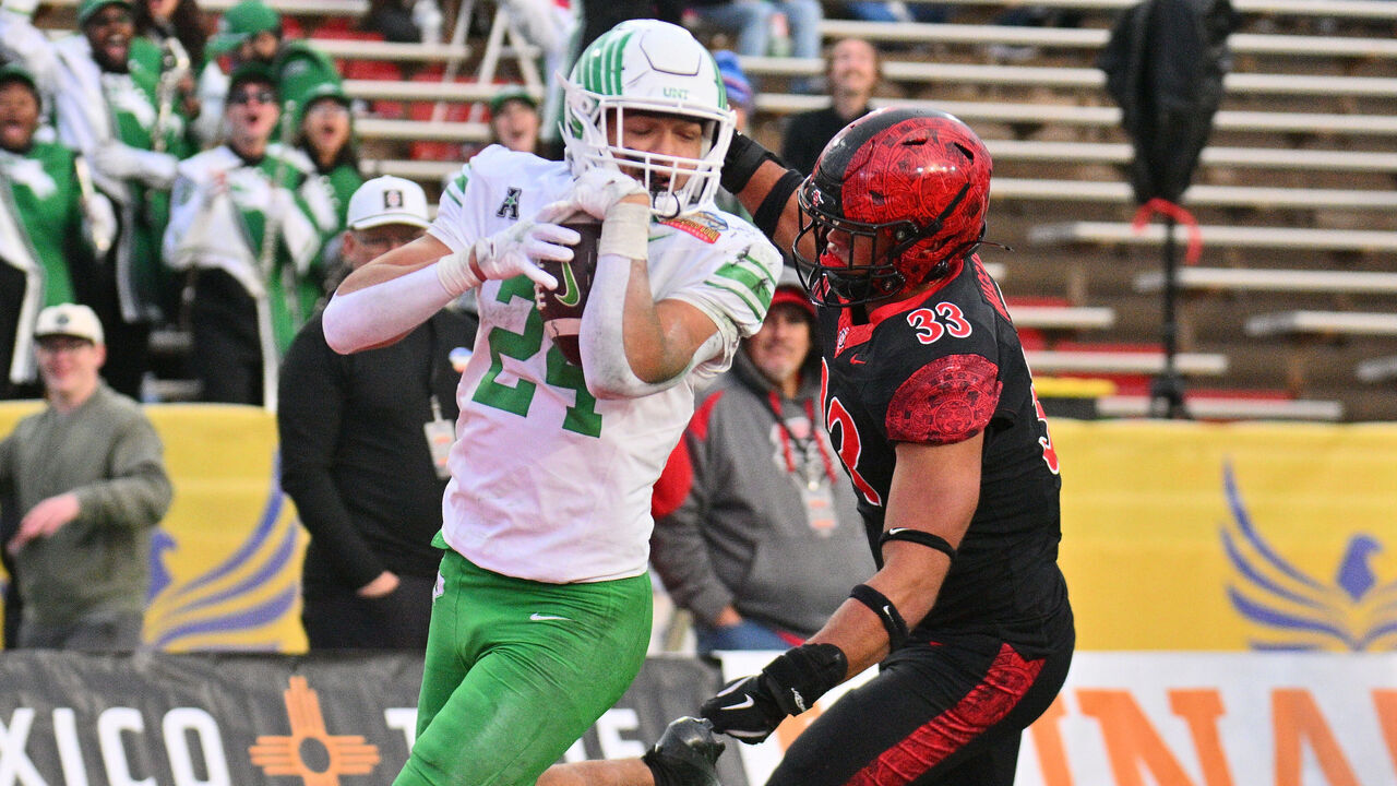 ALBUQUERQUE, NEW MEXICO - DECEMBER 27: Running back Caleb Hawkins #24 of the North Texas Mean Green scores a touchdown against edge rusher Brady Nassar #33 of the San Diego State Aztecs during the first half of the Isleta New Mexico Bowl at University Stadium on December 27, 2025 in Albuquerque, New Mexico.