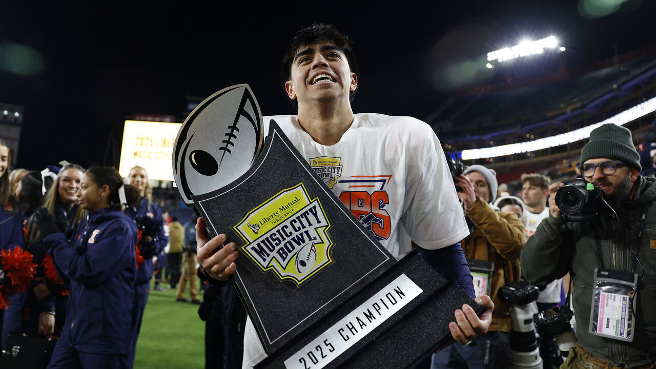 NASHVILLE, TN - DECEMBER 30: Illinois Fighting Illini kicker David Olano (24) walks around the field holding the championship trophy following the Liberty Mutual Music City Bowl between the Tennessee Volunteers and Illinois Fighting Illini, December 30, 2025, at Nissan Stadium in Nashville, Tennessee.