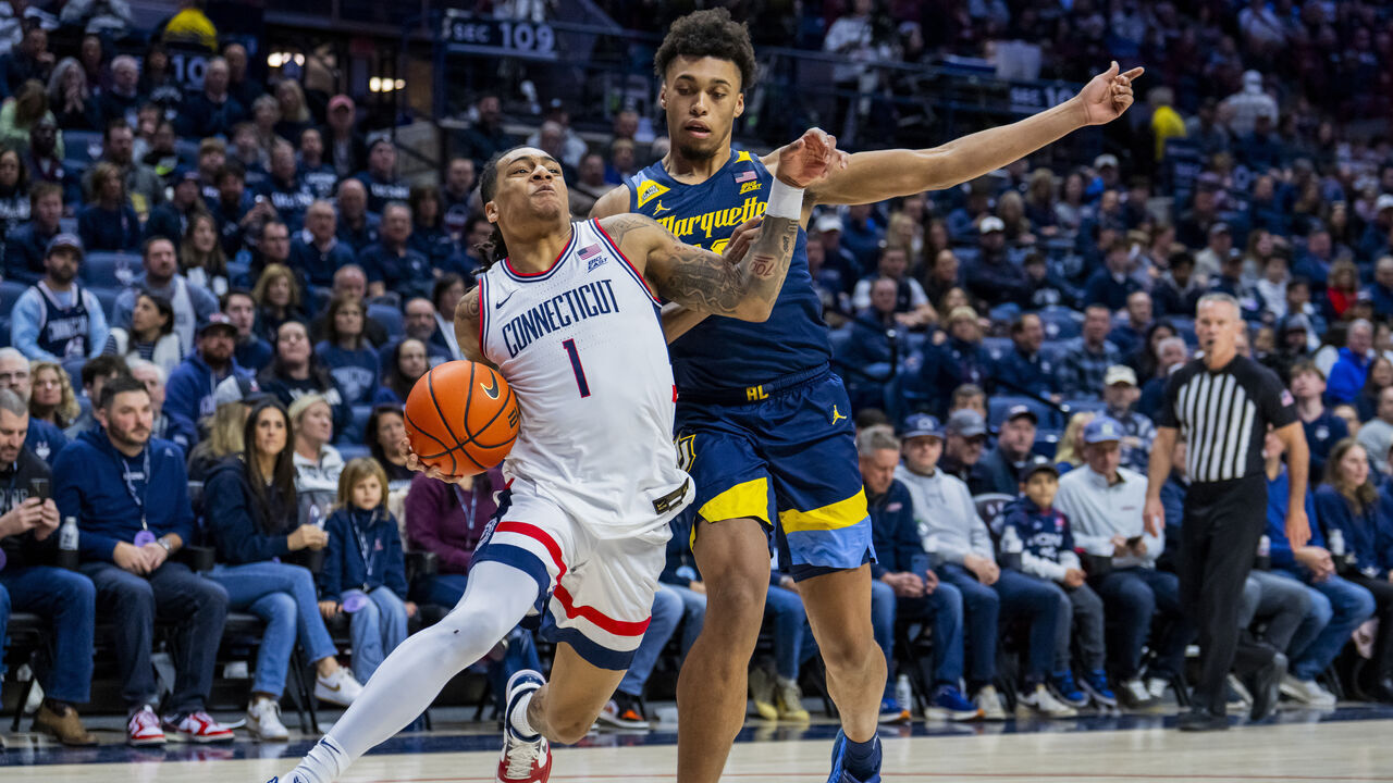 STORRS, CONNECTICUT - JANUARY 04: Solo Ball #1 of the Connecticut Huskies is defended by Caedin Hamilton #18 of the Marquette Golden Eagles during the first half of an NCAA men's basketball game at Harry A. Gampel Pavilion on January 04, 2026 in Storrs, Connecticut.