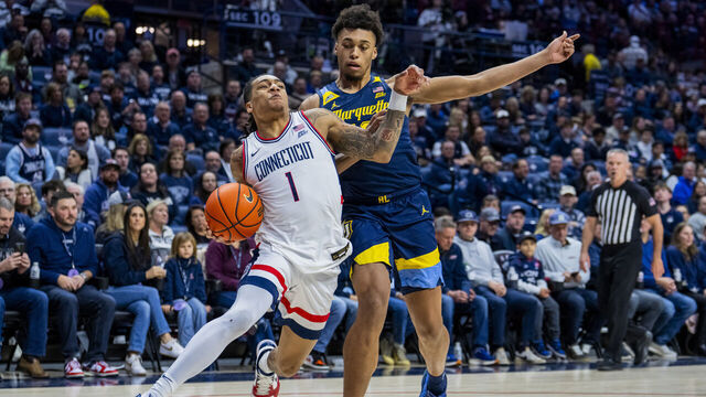 STORRS, CONNECTICUT - JANUARY 04: Solo Ball #1 of the Connecticut Huskies is defended by Caedin Hamilton #18 of the Marquette Golden Eagles during the first half of an NCAA men's basketball game at Harry A. Gampel Pavilion on January 04, 2026 in Storrs, Connecticut.