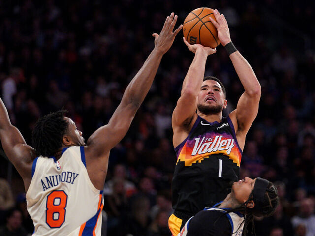 NEW YORK, NEW YORK - JANUARY 17: Devin Booker #1 of the Phoenix Suns shoots as OG Anunoby #8 and Jordan Clarkson #00 of the New York Knicks defend in the second half at Madison Square Garden on January 17, 2026 in New York City.