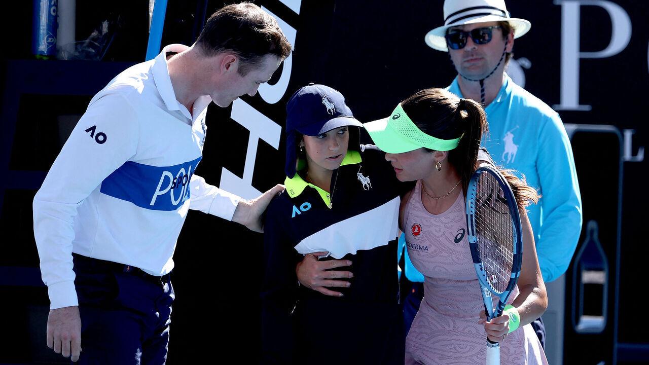 TOPSHOT - Turkey's Zeynep Sonmez assists a ball kid after she fainted during Sonmez's women's singles match against Russia's Ekaterina Alexandrova on day one of the Australian Open in Melbourne on January 18, 2026. / -- IMAGE RESTRICTED TO EDITORIAL USE - STRICTLY NO COMMERCIAL USE --