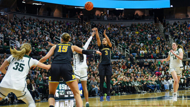 EAST LANSING, MICHIGAN - FEBRUARY 01: Mila Holloway #3 of the Michigan Wolverines attempts a three-point shot over Rashunda Jones #1 of the Michigan State Spartans during the second half of a college basketball game at Breslin Center on February 01, 2026 in East Lansing, Michigan. Michigan won 94-91.
