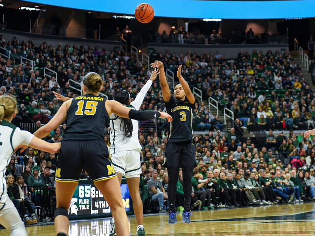 EAST LANSING, MICHIGAN - FEBRUARY 01: Mila Holloway #3 of the Michigan Wolverines attempts a three-point shot over Rashunda Jones #1 of the Michigan State Spartans during the second half of a college basketball game at Breslin Center on February 01, 2026 in East Lansing, Michigan. Michigan won 94-91.