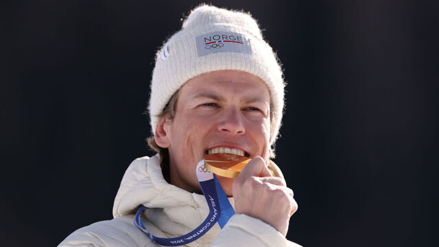 VAL DI FIEMME, ITALY - FEBRUARY 08: Gold medalist Johannes Hoesflot Klaebo of Team Norway bites his medal during the medal ceremony for the Men's 10km + 10km Skiathlon on day two of the Milano Cortina 2026 Winter Olympic games at Tesero Cross-Country Skiing Stadium on February 08, 2026 in Val di Fiemme, Italy.