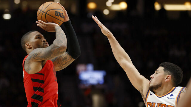 PORTLAND, OREGON - OCTOBER 21: Damian Lillard #0 of the Portland Trail Blazers shoots against Devin Booker #1 of the Phoenix Suns at Moda Center on October 21, 2022 in Portland, Oregon.