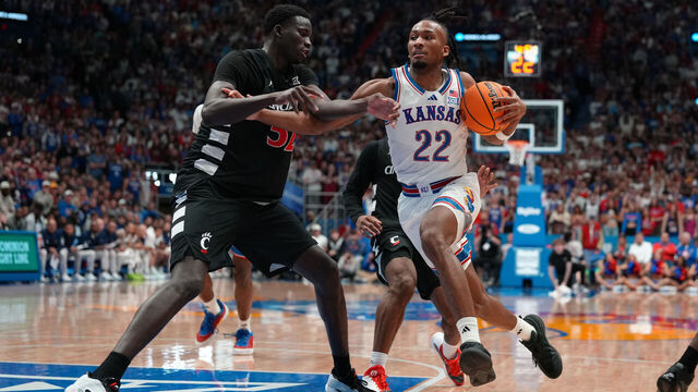LAWRENCE, KANSAS - FEBRUARY 21: Guard Darryn Peterson #22 of the Kansas Jayhawks drives against center Moustapha Thiam #52 of the Cincinnati Bearcats in the first half at Allen Fieldhouse on February 21, 2026 in Lawrence, Kansas.