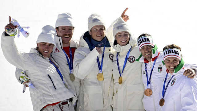 (From L) Silver medallists USA's Ben Ogden and USA's Gus Schumacher, gold medallists Norway's Johannes Hoesflot Klaebo and Norway's Einar Hedegart and bronze medallists Italy's Federico Pellegrino and Italy's Elia Barp celebrate on the podium for the men's team cross country free sprint final event of the Milano Cortina 2026 Winter Olympic Games at Tesero Cross-Country Skiing Stadium in Lago di Tesero (Val di Fiemme), on February 18, 2026.