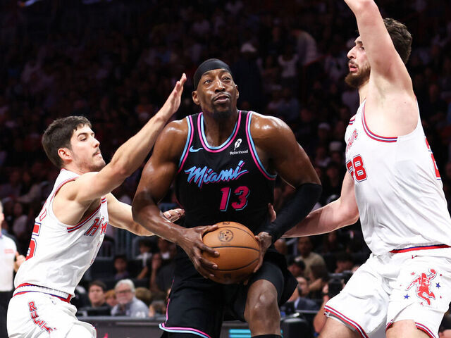 MIAMI, FLORIDA - FEBRUARY 28: Bam Adebayo #13 of the Miami Heat drives against Reed Sheppard #15 and Alperen Sengun #28 of the Houston Rockets during the second quarter of the game at Kaseya Center on February 28, 2026 in Miami, Florida.