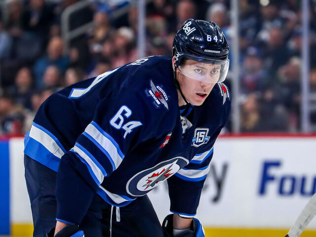 WINNIPEG, CANADA - MARCH 3: Logan Stanley #64 of the Winnipeg Jets looks on during a first period stoppage in play against the Chicago Blackhawks at the Canada Life Centre on March 3, 2026 in Winnipeg, Manitoba, Canada. The Jets defeated the Hawks 3-2 in overtime.