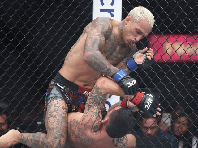 LAS VEGAS, NEVADA - MARCH 07: Charles Oliveira of Brazil strikes Max Holloway of the United States during their BMF title bout at T-Mobile Arena on March 07, 2026 in Las Vegas, Nevada.