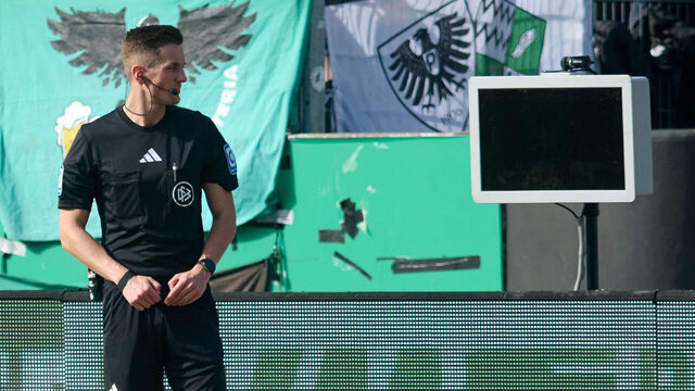 dpatop - 08 March 2026, North Rhine-Westphalia, Münster: Soccer, Men: Bundesliga 2, Preußen Münster - Hertha BSC, Matchday 25, Preußenstadion. Referee Felix Bickel stands in front of the dark screen as he tries to review a VAR decision on a penalty kick for Berlin. Photo: Bernd Thissen/dpa - IMPORTANT NOTE: In accordance with the regulations of the DFL German Football League and the DFB German Football Association, it is prohibited to utilize or have utilized photographs taken in the stadium and/or of the match in the form of sequential images and/or video-like photo series.