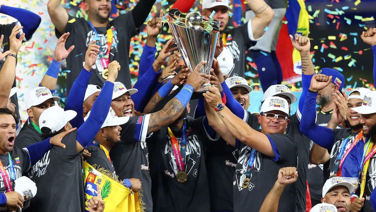 MIAMI, FLORIDA - MARCH 17: Salvador Perez #13 and manager Omar López #22 of Team Venezuela lift the championship trophy after defeating Team United States 3-2 at loanDepot park on March 17, 2026 in Miami, Florida.