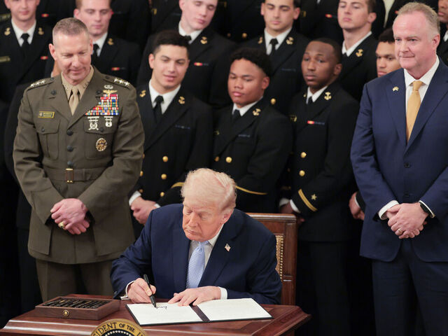 WASHINGTON, DC - MARCH 20: U.S. President Donald Trump displays an executive order he signed titled "Preserving America's Game" to preserve the broadcast time slot for the Army v Navy football game during a ceremony awarding the Commander-in-Chief Trophy to the Navy Midshipmen football team in the East Room of the White House March 20, 2026 in Washington, DC. The Commander-in-Chief Trophy is awarded each year to the winner of the Army-Navy football game.