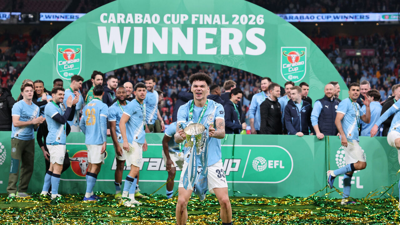 Manchester City's English midfielder #33 Nico O'Reilly poses with the trophy as City players celebrate after the English League Cup final football match between Arsenal and Manchester City at Wembley Stadium in London on March 22, 2026. Nico O'Reilly scored both goals as City won the game 2-0. / RESTRICTED TO EDITORIAL USE. No use with unauthorized audio, video, data, fixture lists, club/league logos or 'live' services. Online in-match use limited to 120 images. An additional 40 images may be used in extra time. No video emulation. Social media in-match use limited to 120 images. An additional 40 images may be used in extra time. No use in betting publications, games or single club/league/player publications. /
