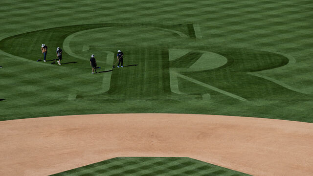 DENVER, CO - APRIL 2: Grounds crews use brooms to brush the Colorado Rockies' logo into the outfield grass on Thursday, April 2, 2026, at Coors Field in Denver, Colo.
