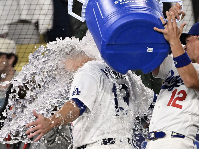 Los Angeles, CA - April 10: Alex Call #12 dumps the water bucket on Max Muncy #13 of the Los Angeles Dodgers after he hit a walk off home run and his third home run of the night against the Texas Rangers in the ninth inning of a baseball game at Dodger Stadium in Los Angeles on Friday, April 10, 2026. Dodgers won 8-7.