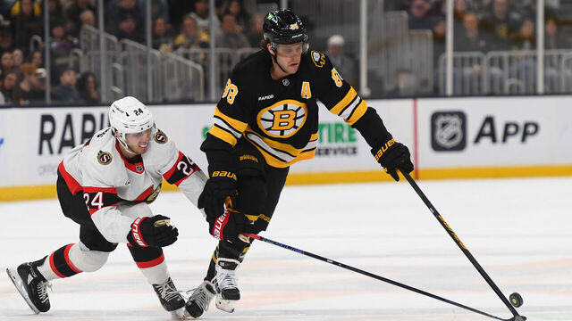 BOSTON, MASSACHUSETTS - DECEMBER 21: David Pastrnak #88 of the Boston Bruins skates with the puck against Dylan Cozens #24 of the Ottawa Senators at the TD Garden on December 21, 2025 in Boston, Massachusetts.