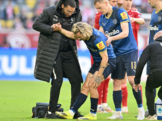 10 April 2026, North Rhine-Westphalia, Duesseldorf: Soccer, Men: Bundesliga 2, Fortuna Düsseldorf - Holstein Kiel, Matchday 29, Merkur Spiel-Arena. John Tolkin (Holstein Kiel) is injured, (r) Ivan Nekic (Holstein Kiel) helps him up. Photo: Anke Waelischmiller/dpa - IMPORTANT NOTE: In accordance with the regulations of the DFL German Football League and the DFB German Football Association, it is prohibited to utilize or have utilized photographs taken in the stadium and/or of the match in the form of sequential images and/or video-like photo series.