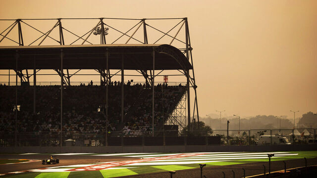 German Red Bull Racing Formula One team racing driver Sebastian Vettel driving his RB9 racing car around Turn One of the circuit while being watched by hundreds of fans and spectators sitting and standing in the start and finish straight Turn One grandstand, alongside Airtel advertising signs and hoardings during the 2013 Indian Grand Prix, Buddh International Circuit, Greater Noida, India, on the 27th October 2013.