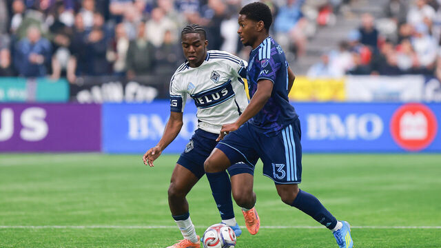 VANCOUVER, BRITISH COLUMBIA - APRIL 17: Bruno Caicedo #14 of the Vancouver Whitecaps fights for possession with Justin Reynolds #13 of the Sporting Kansas City during the match at BC Place on April 17, 2026 in Vancouver, British Columbia.