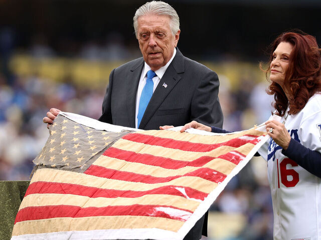 LOS ANGELES, CALIFORNIA - APRIL 25: Rick and Barbaralee Monday display the flag he saved from burning in center field for its 50th anniversary before the game between the Chicago Cubs and Los Angeles Dodgers at Dodger Stadium on April 25, 2026 in Los Angeles, California.
