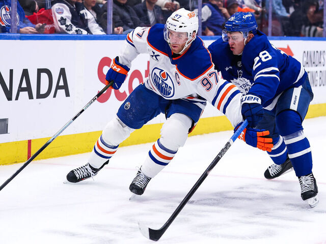 TORONTO, CANADA - DECEMBER 13: Connor McDavid #97 of the Edmonton Oilers controls the puck against Troy Stecher #28 of the Toronto Maple Leafs at Scotiabank Arena on December 13, 2025 in Toronto, Ontario, Canada.
