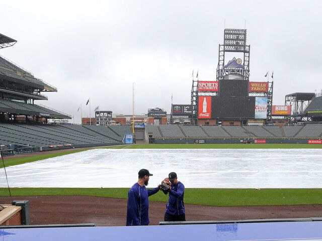 DENVER, CO - APRIL 26: John Axford #66 (L) and Scott Oberg #45 of the Colorado Rockies walk off the field after playing catch in the rain at Coors Field on April 26, 2015 in Denver, Colorado.The game between the San Francisco Giants and Colorado Rockies has been postponed due to rain.