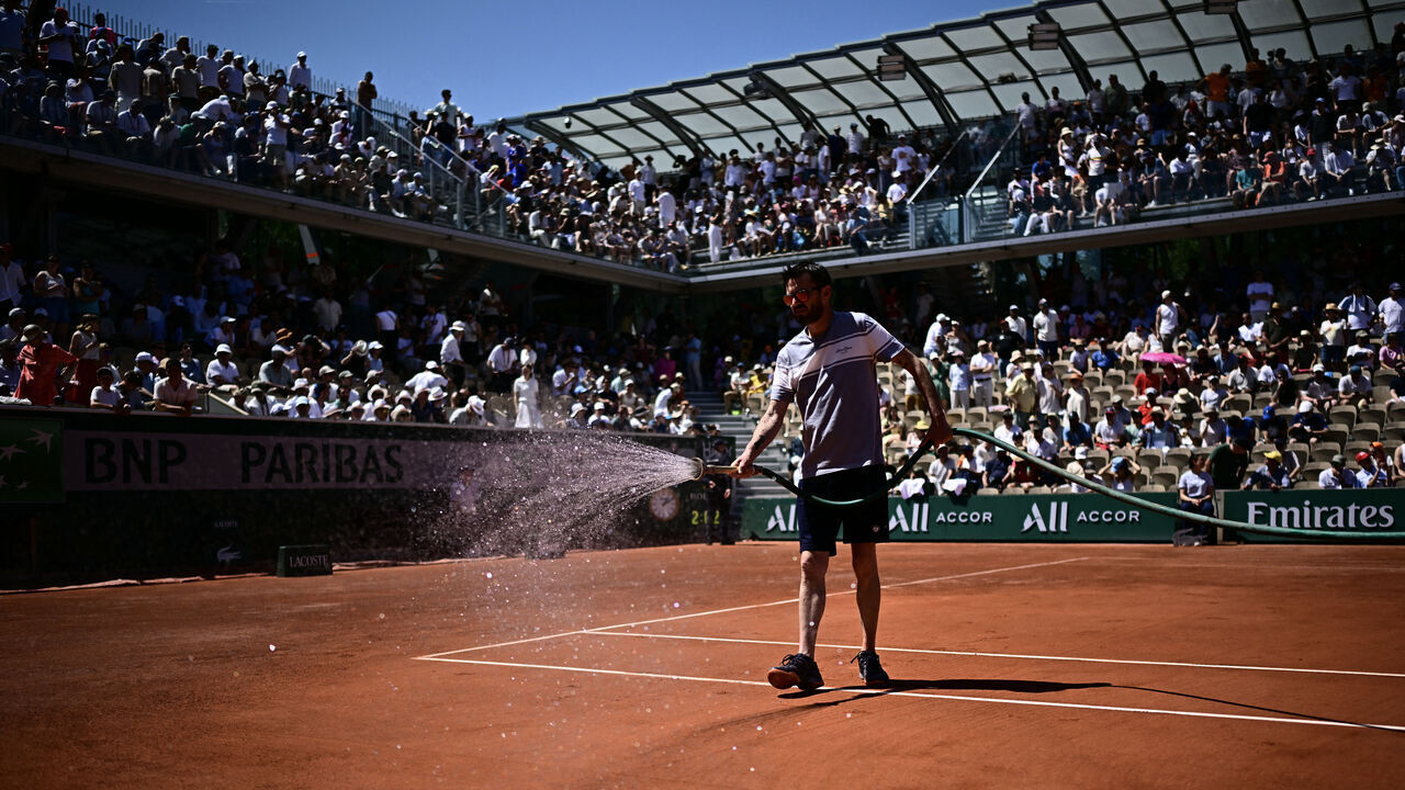 A member of the Grounds Staff sprays water on the clay of Court Simonne-Mathieu during a men's singles match on day 3 of the French Open tennis tournament at the Roland-Garros Complex in Paris on May 26, 2026.