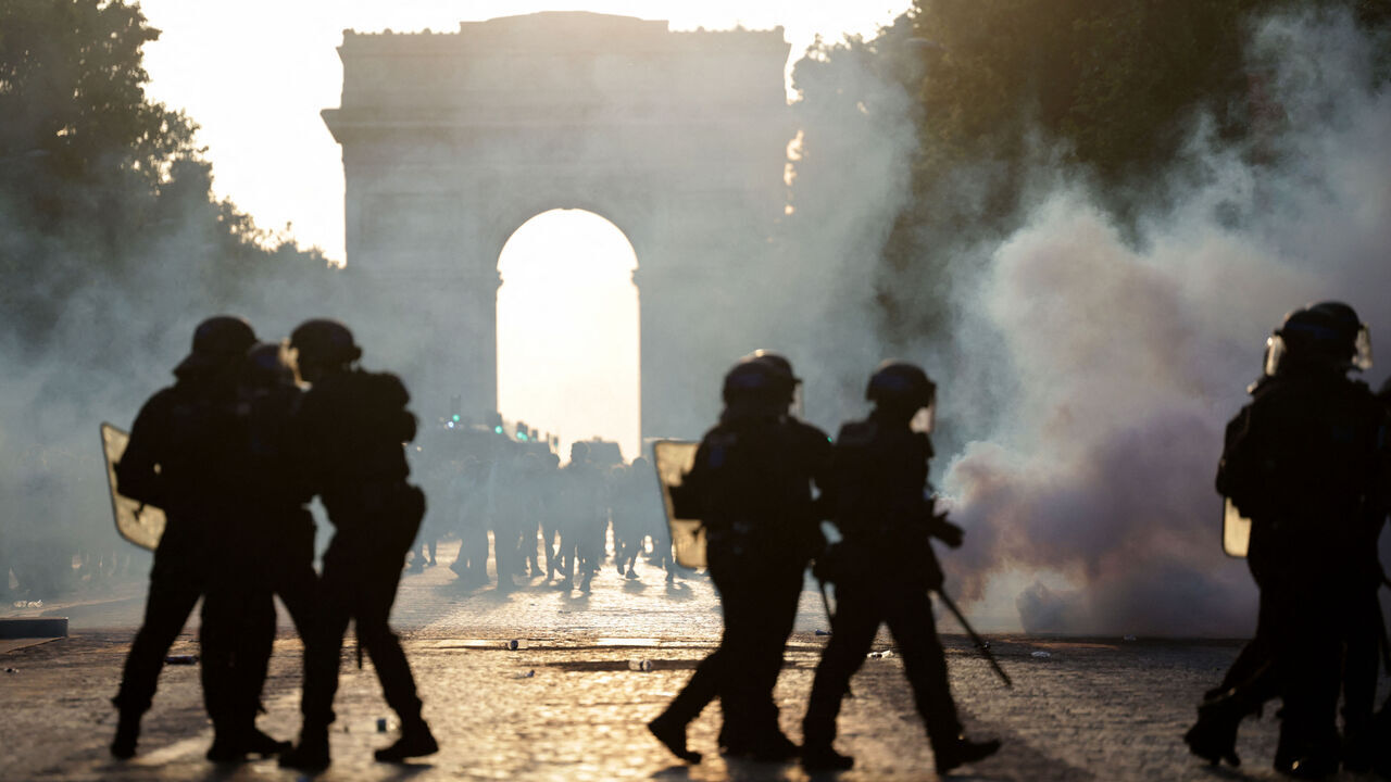 TOPSHOT - French Republican Security Corps (CRS - Compagnies Republicaines de Securite) Police officers walk amid smoke from teargas on the Champs-Elysees Avenue, during the UEFA Champions League final football match between Paris Saint-Germain (PSG) and Arsenal FC played in Budapest, in Paris on May 30, 2026.