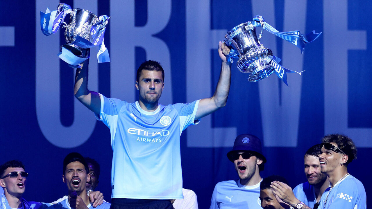 MANCHESTER, ENGLAND - MAY 25: Rodri of Manchester City lifts the Carabao Cup and FA Cup trophies as the bus carrying the men's team arrives during the After Party Celebration to mark the achievements of Manchester City men’s, women’s and academy teams during the 25/26 season at The Co-op Live Arena on May 25, 2026 in Manchester, England.